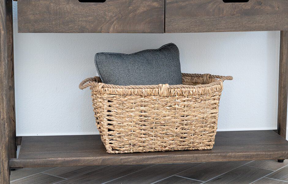 A woven basket with a cushion on a wooden shelving unit.