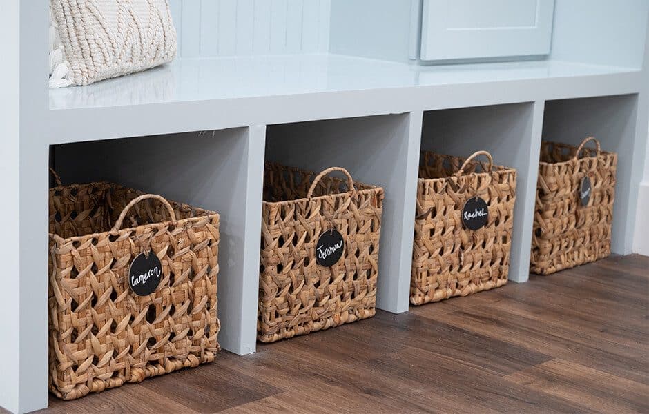 Mudroom with a light blue bench and four labeled woven baskets underneath