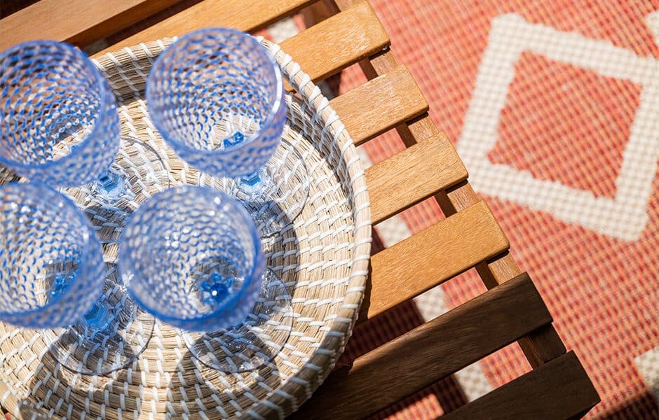 Wicker tray with blue glasses on wooden table