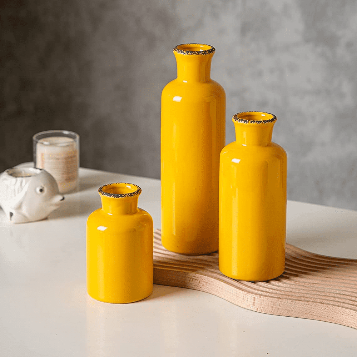 Set of three yellow ceramic vases with gold-trimmed rims and a decorative wooden tray