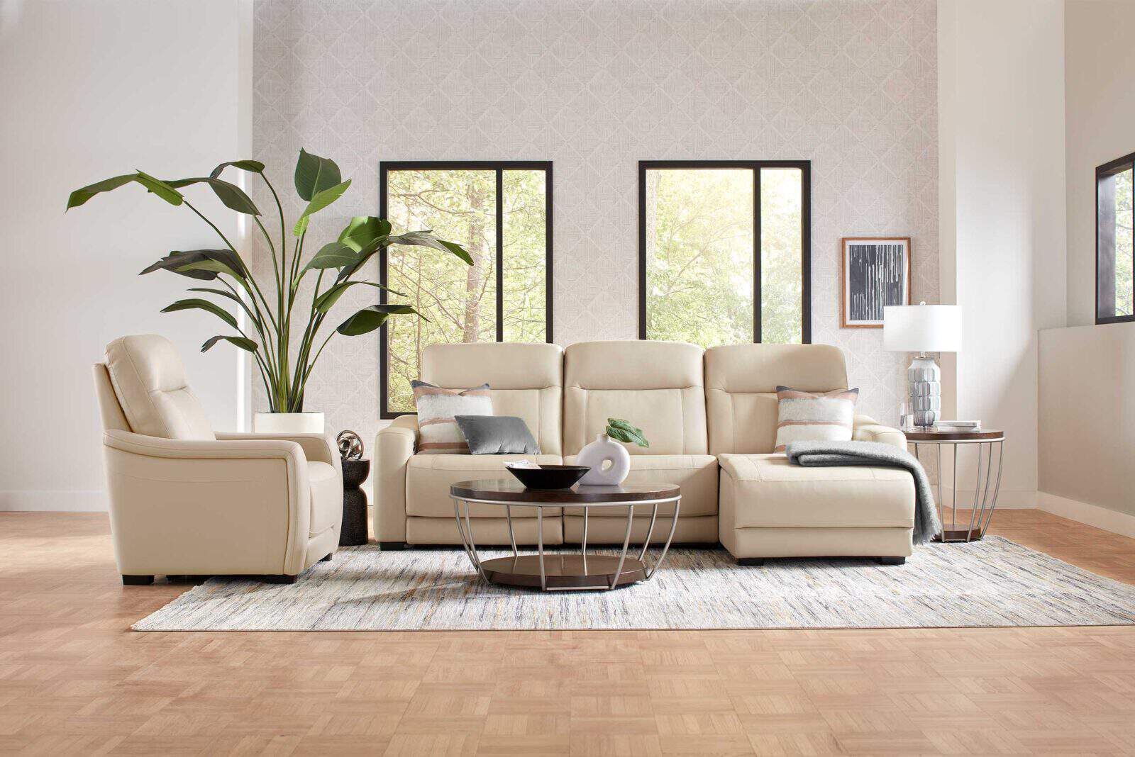 Living room with cream leather sectional, recliner, round coffee table, and large plant