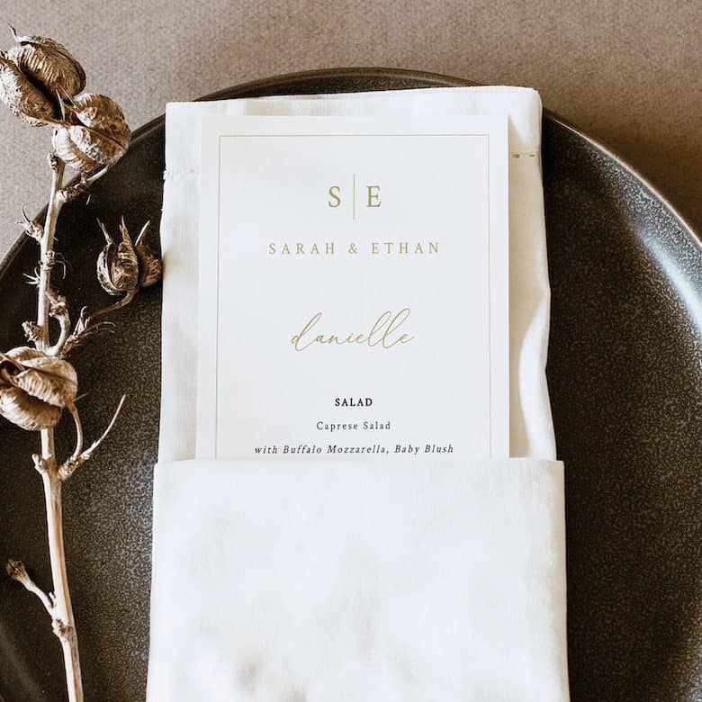Wedding place card in napkin on dark plate with dried foliage