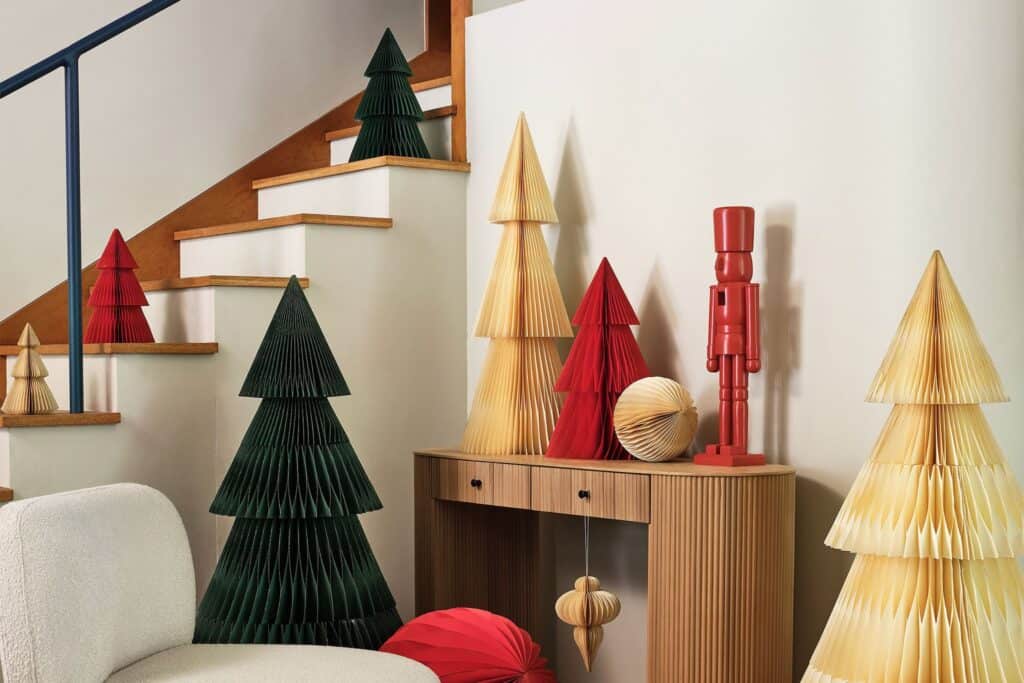 Colorful paper Christmas trees and decorations arranged by a staircase with a red nutcracker figure
