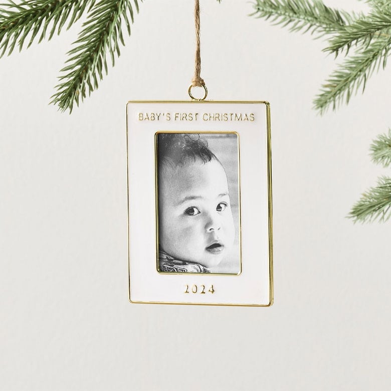 Baby’s first Christmas photo ornament with gold frame and 2024 engraving hanging on a tree branch