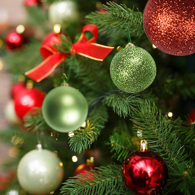 Christmas tree decorated with red, green, and gold ornaments and a red ribbon bow