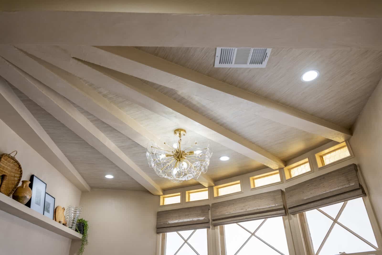 Ceiling with exposed wooden beams, modern gold chandelier, recessed lighting, and high transom windows