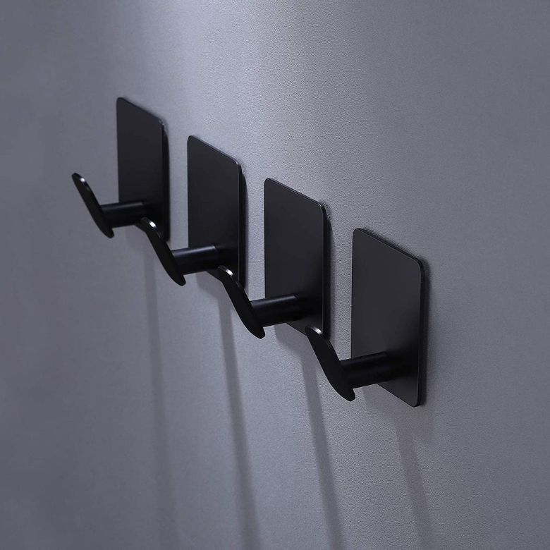 Set of four black metal wall hooks mounted in a row on a gray wall