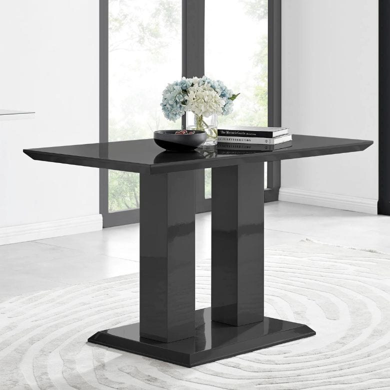 Black glossy rectangular dining table with dual pedestal base, decorated with flowers and books