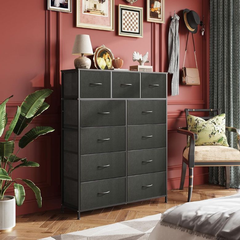 Tall black dresser with multiple drawers in a red-walled bedroom, decorated with framed art and accessories