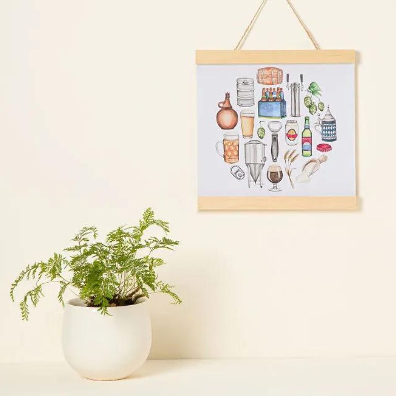 Colorful kitchen-themed wall art hanging above a white pot with a green leafy plant