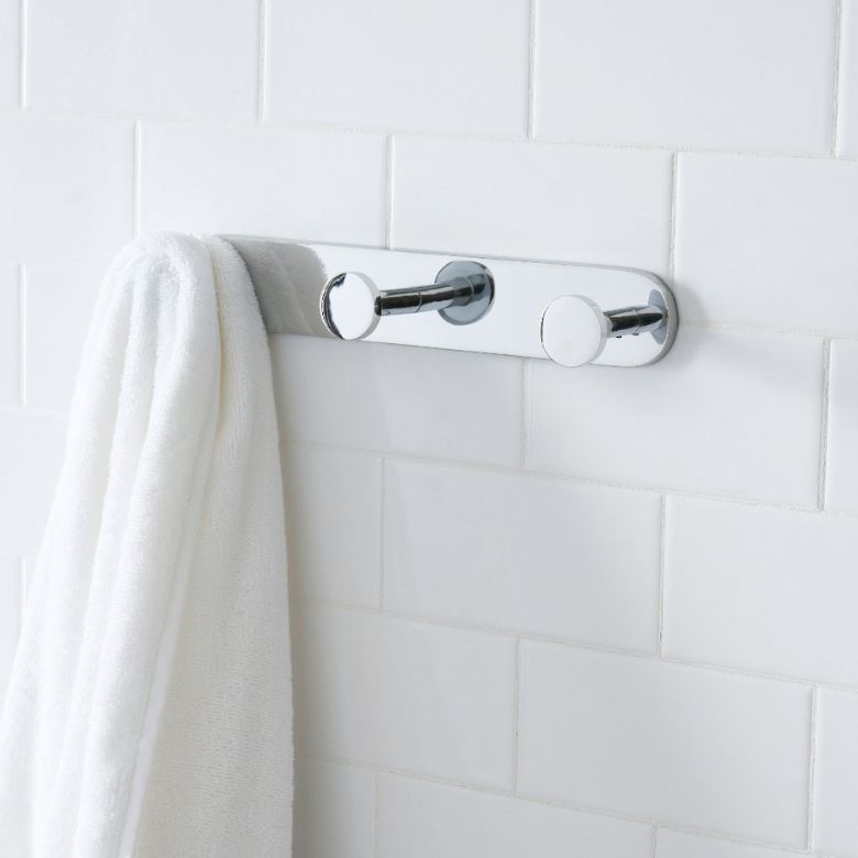 Chrome towel hook bar mounted on white tiled wall