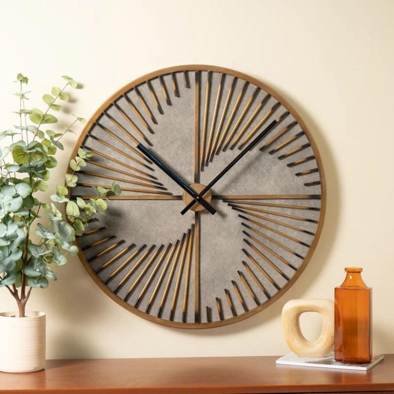 Round geometric wall clock above a shelf with a plant and decorative items.