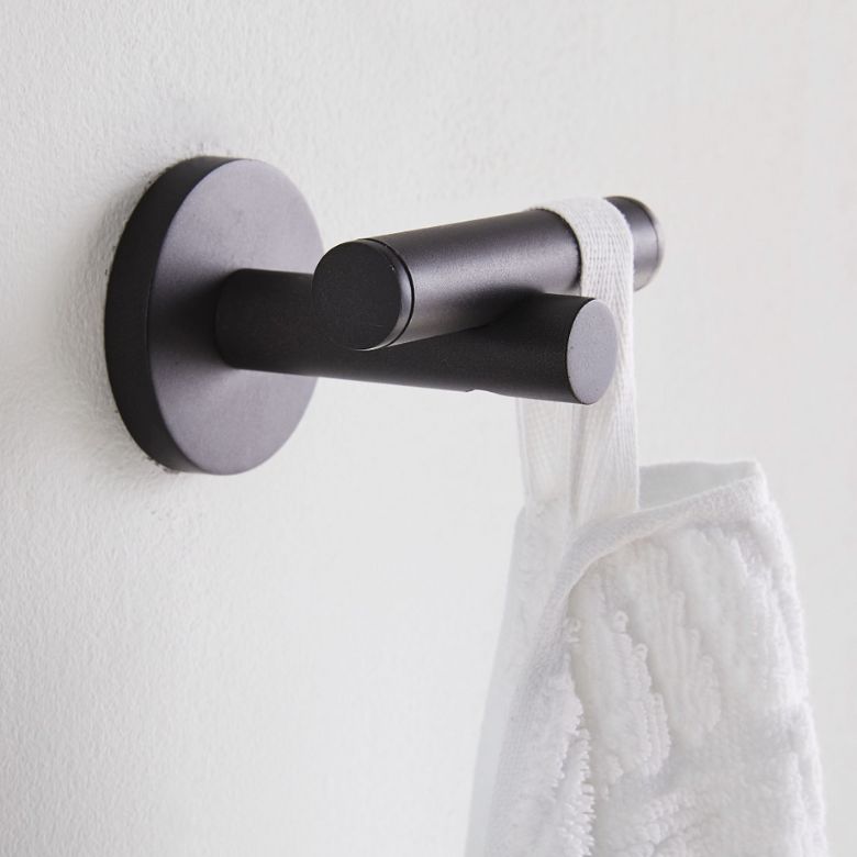 Black metal wall hook holding a white textured towel.