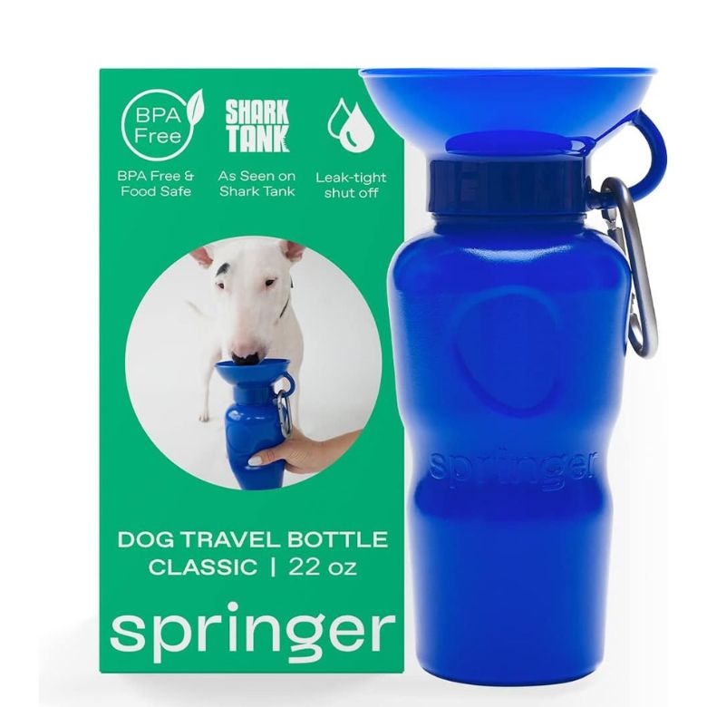 Blue Springer dog travel water bottle with attached bowl, shown beside its green BPA-free packaging.