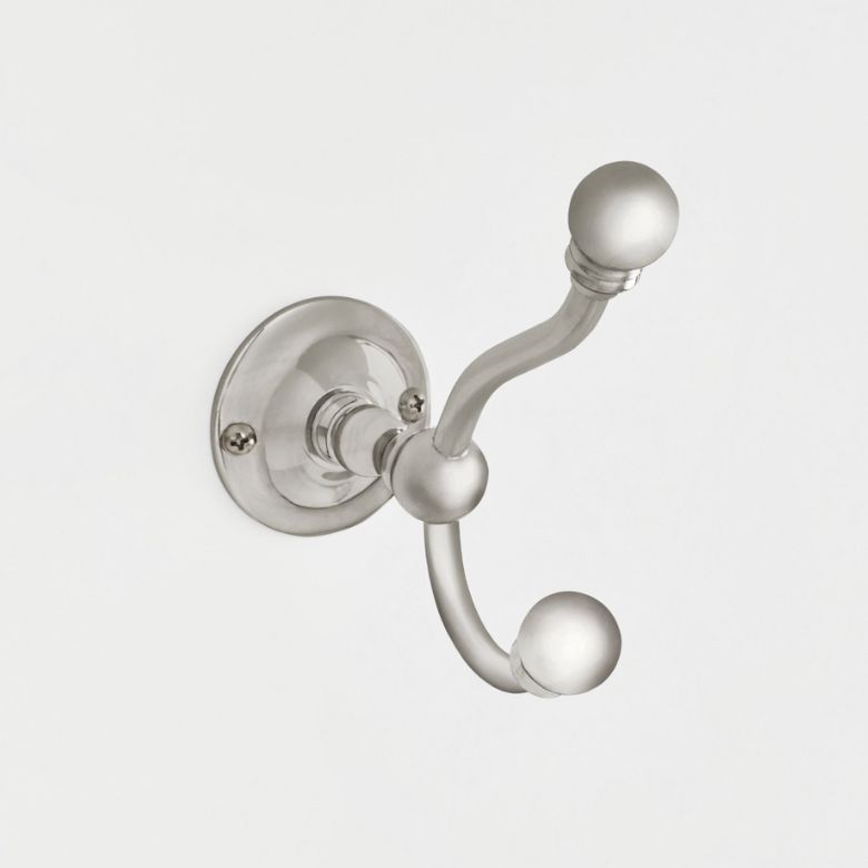 Silver double wall hook with rounded ends mounted on a white wall.