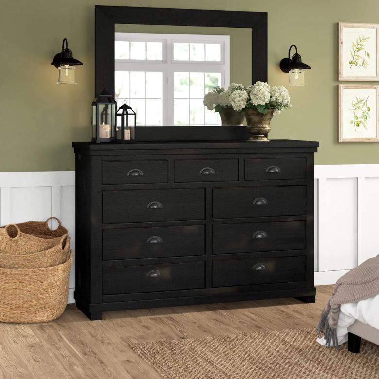 Black dresser with mirror, brass handles, and decorative accents in a cozy bedroom.