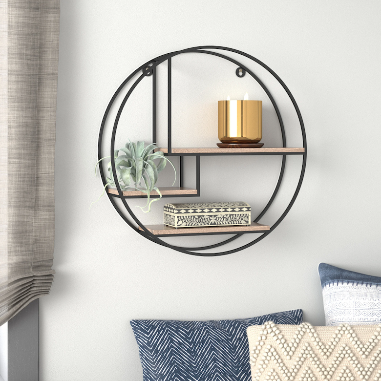 Round metal wall shelf with wooden tiers holding a candle, plant, and decorative box.