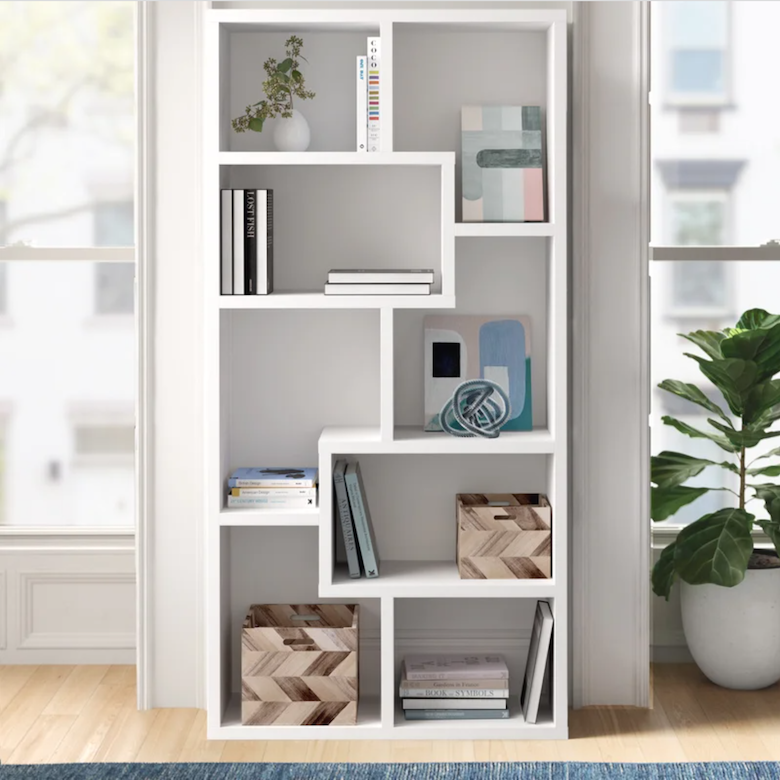 White geometric bookshelf filled with books, decor, and patterned storage bins.