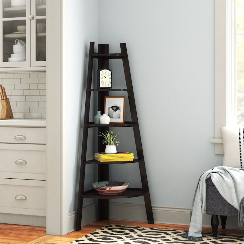 Black corner ladder shelf decorated with books, vases, and framed photos.