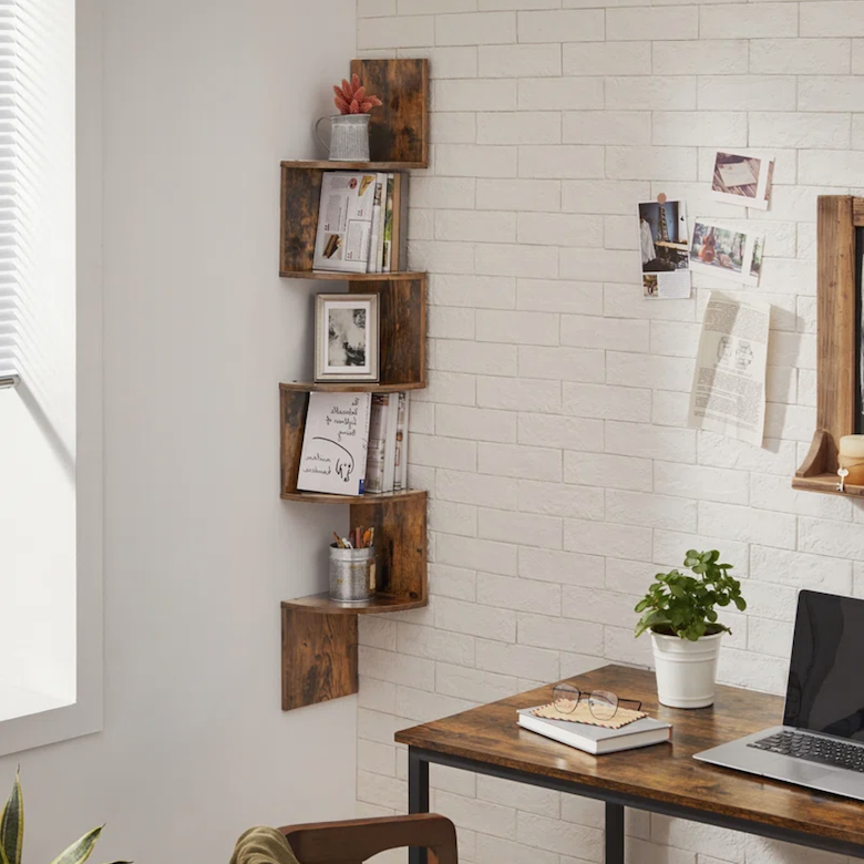 Cozy home office with a wooden corner shelf, brick wall accents, and a desk with a plant and laptop.
