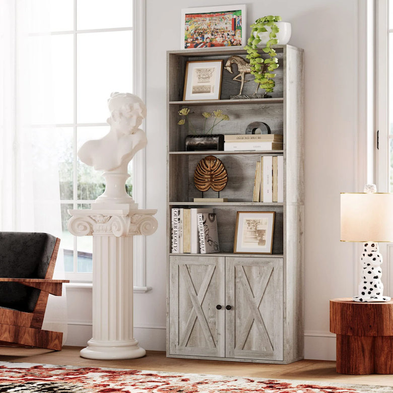 Living room corner with a gray farmhouse bookshelf, decorative art, and a bust on a pedestal.