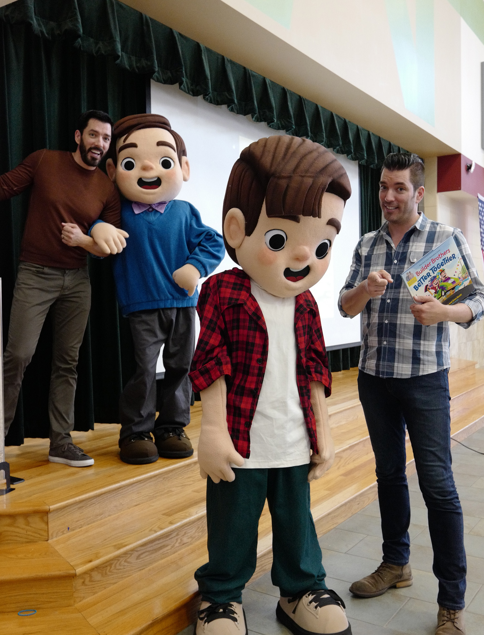 Drew and Jonathan standing with large cartoon character mascots on a stage.