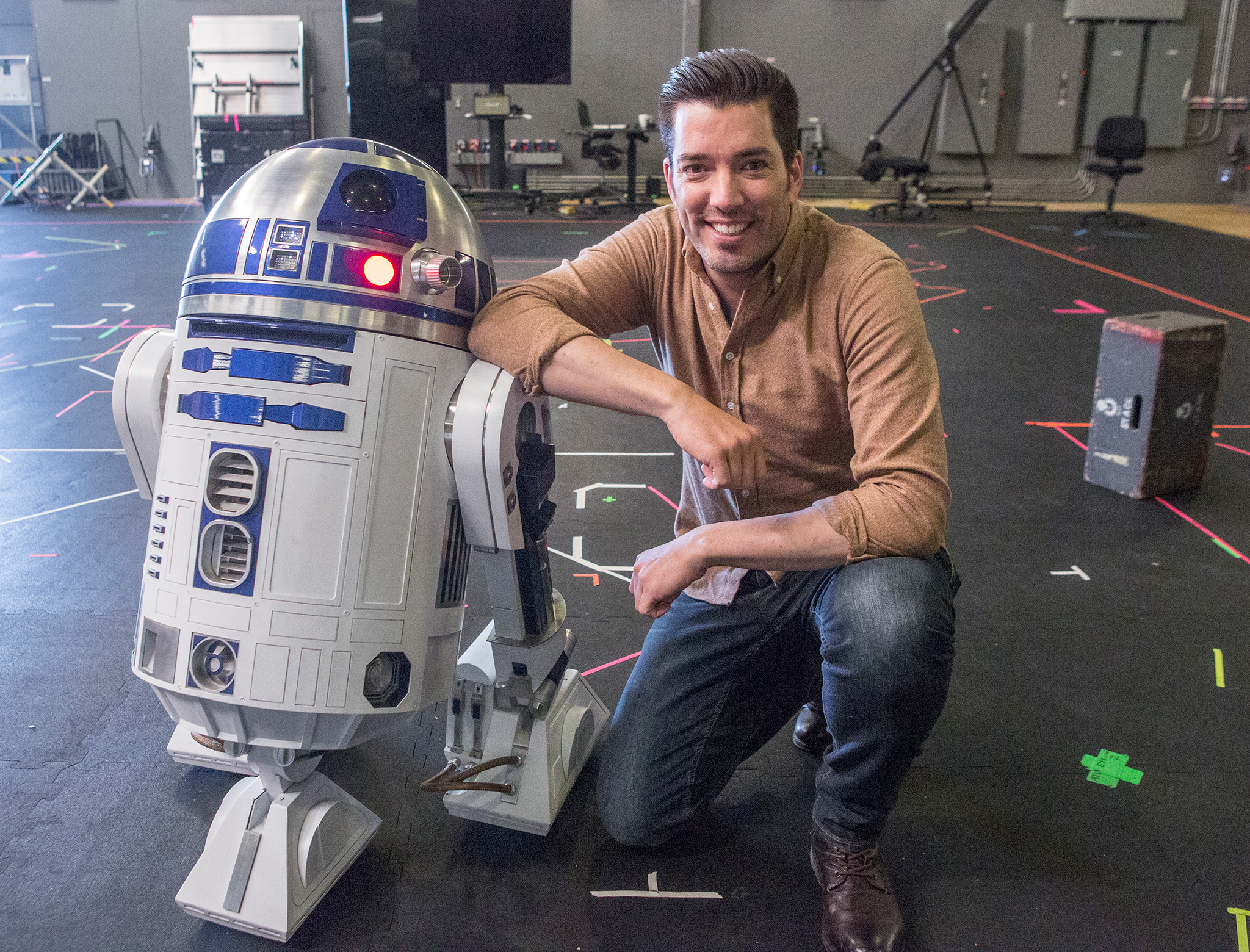 Jonathan kneeling beside an R2-D2 robot replica in a studio setting.
