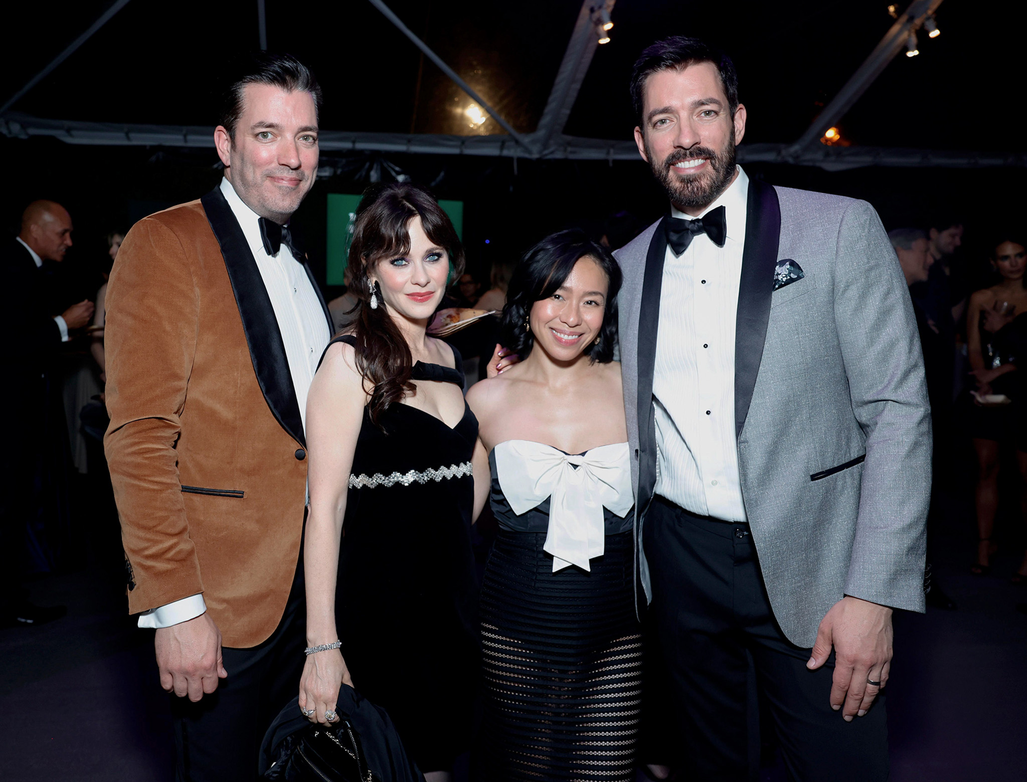 Group of four people dressed in formal evening attire posing together at an event.