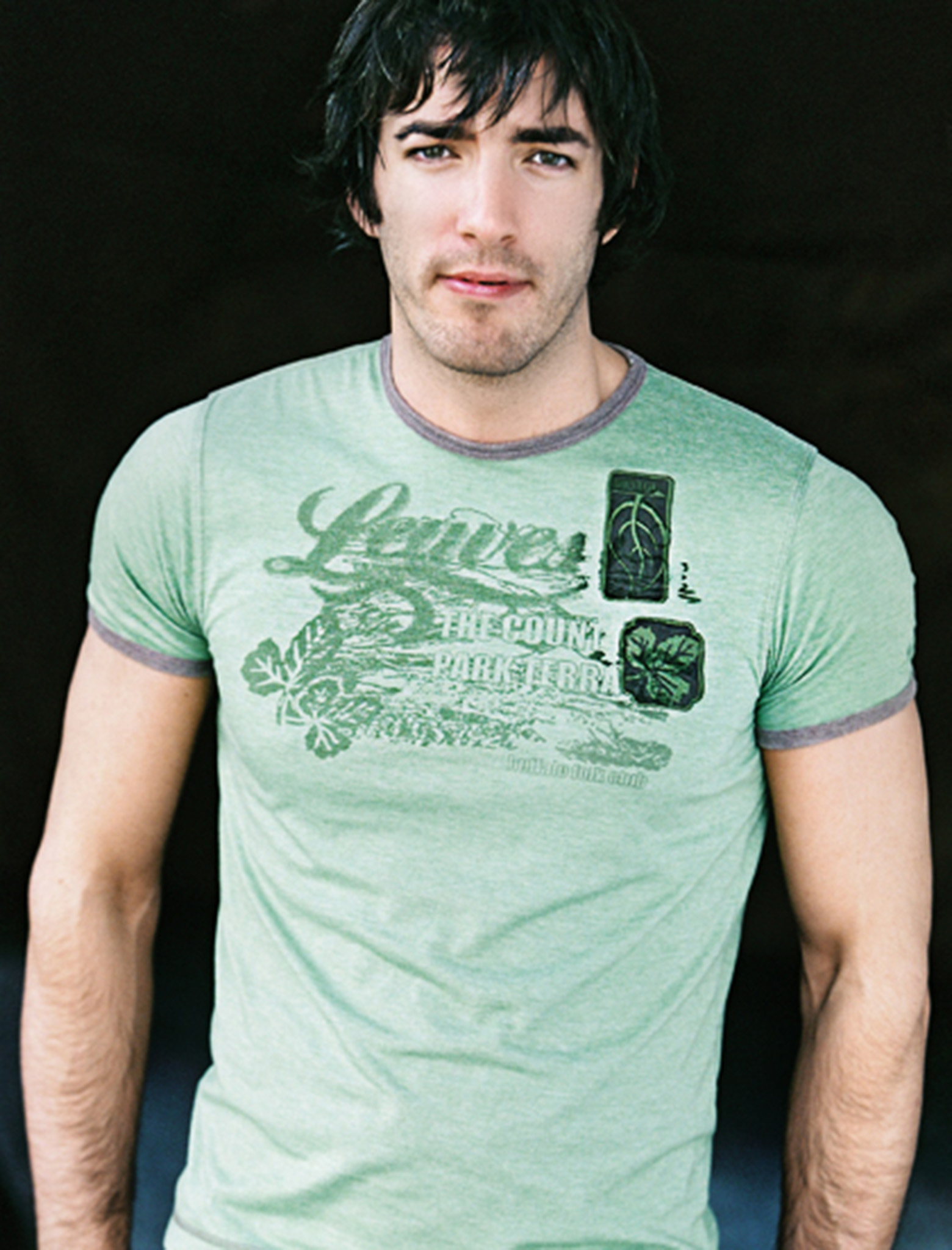 Drew in a light green graphic T-shirt standing against a dark background.