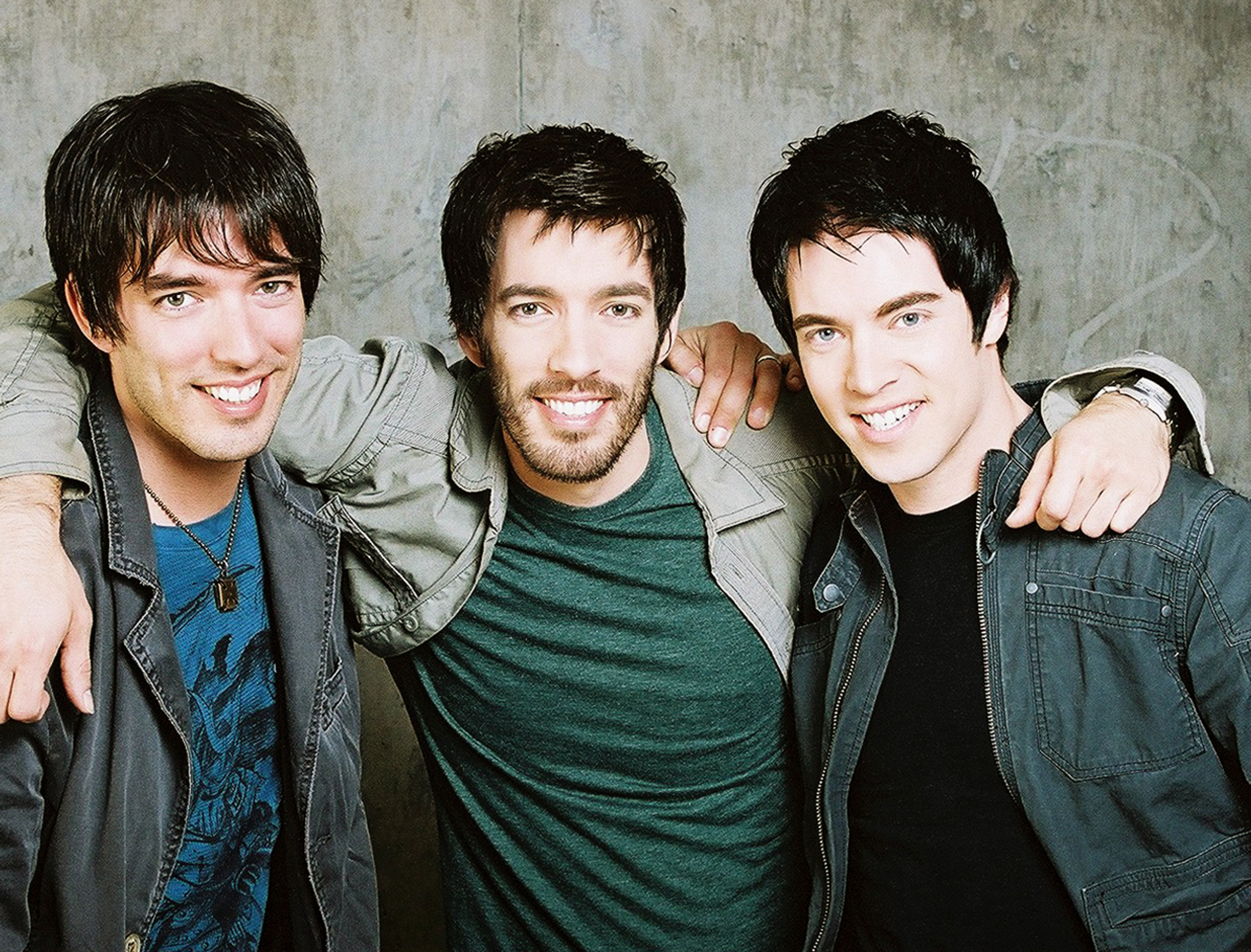 Scott Brothers men standing close together with their arms around each other, smiling at the camera.