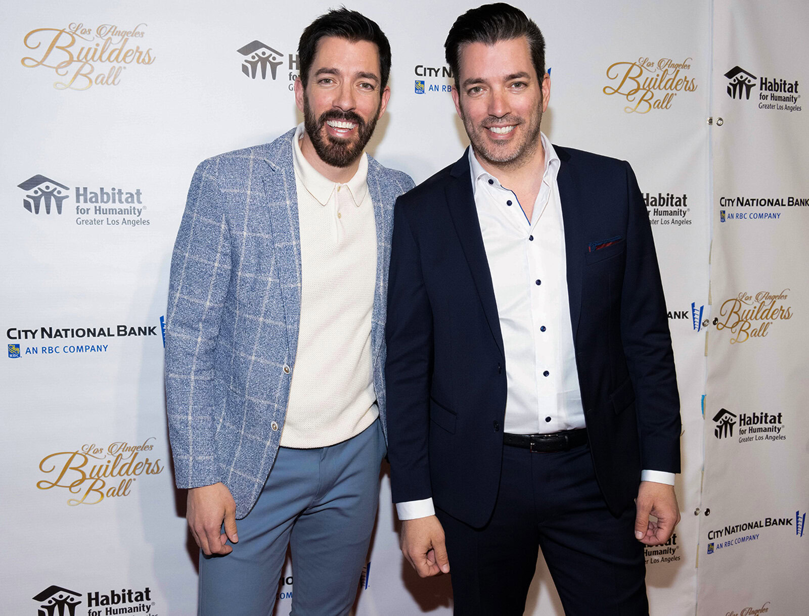 Drew and Jonathan dressed in suits posing together on a red carpet at an event.