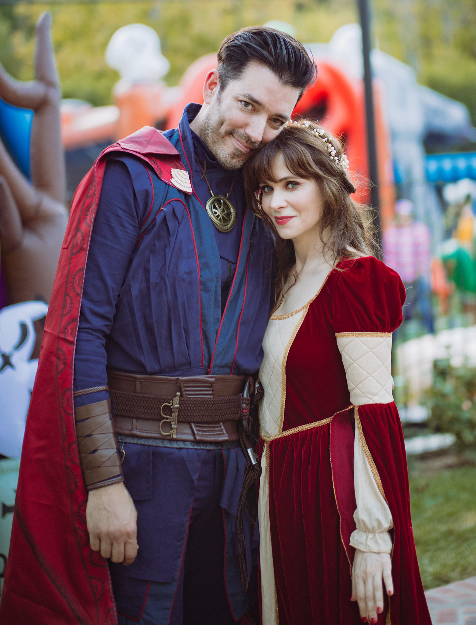 Jonathan and Zooey dressed in elaborate costumes, Jonathan in a wizard outfit and Zooey in a red medieval-style gown.