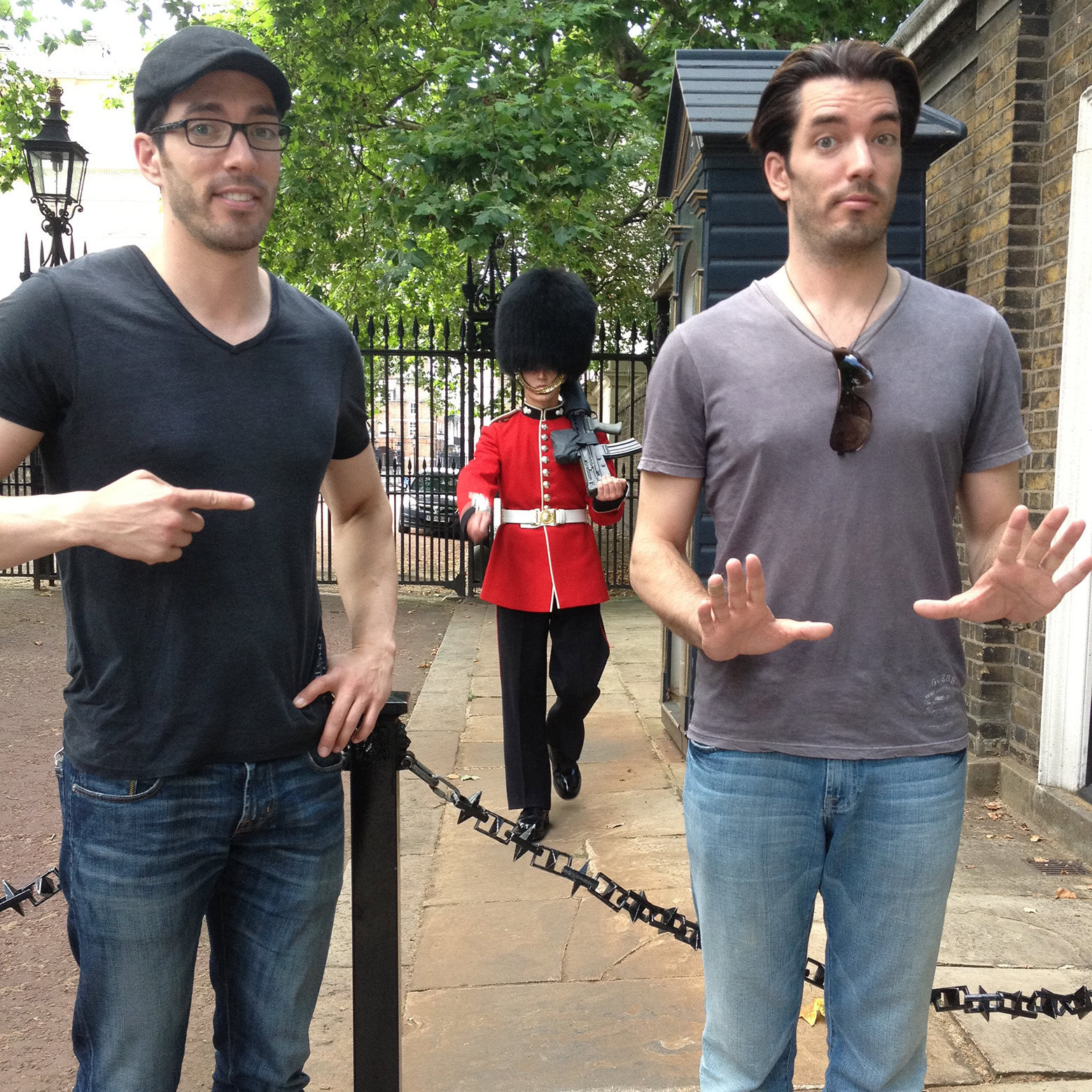 Drew and Jonathan posing playfully near a marching guard in a red uniform and bearskin hat.