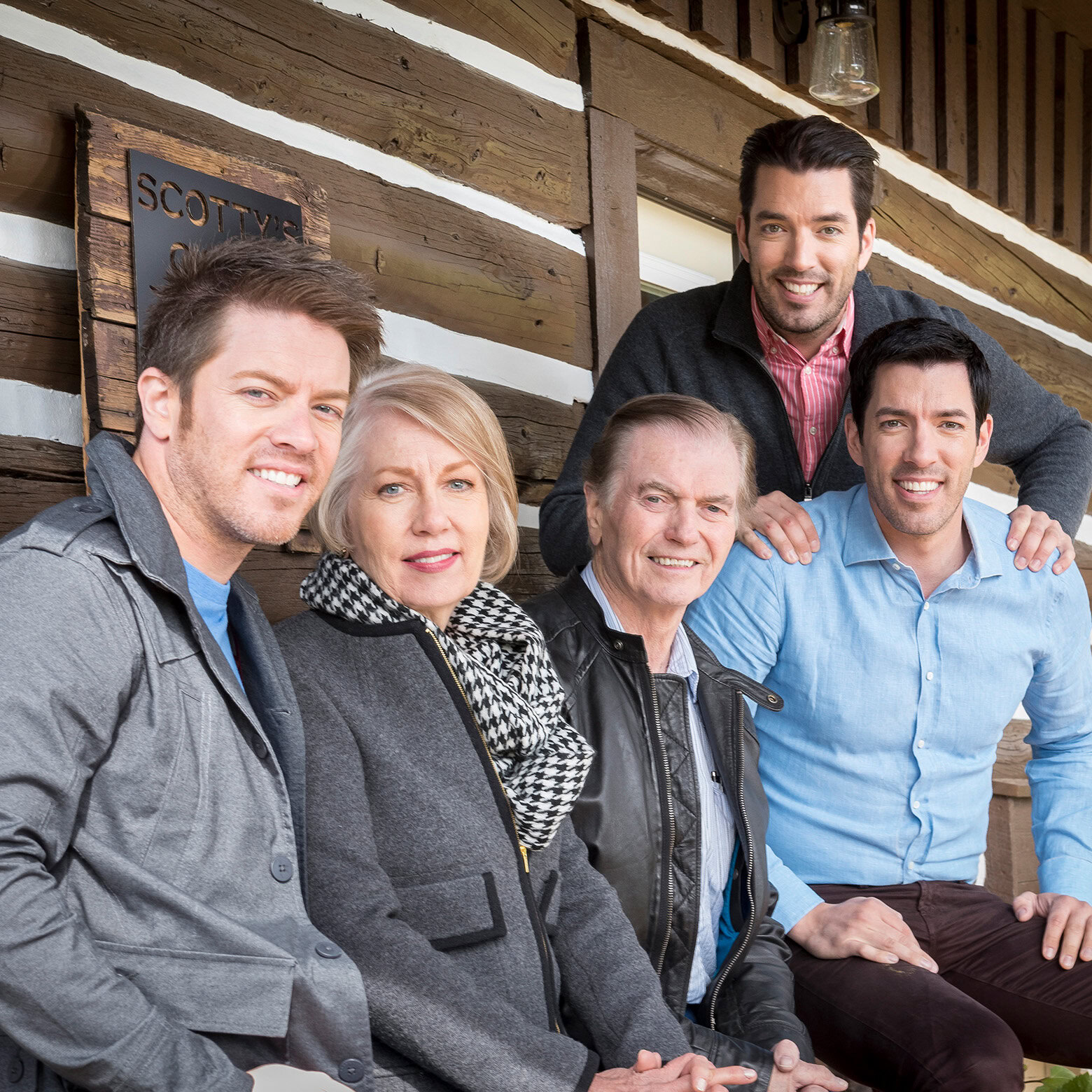 Scott family sitting together outside a rustic wooden building, smiling for the photo.