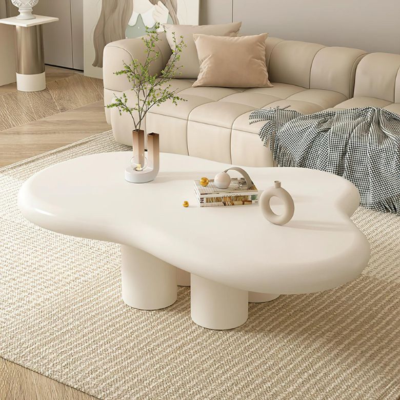 Beige living room with curved sofa and sculptural white coffee table on a textured rug.
