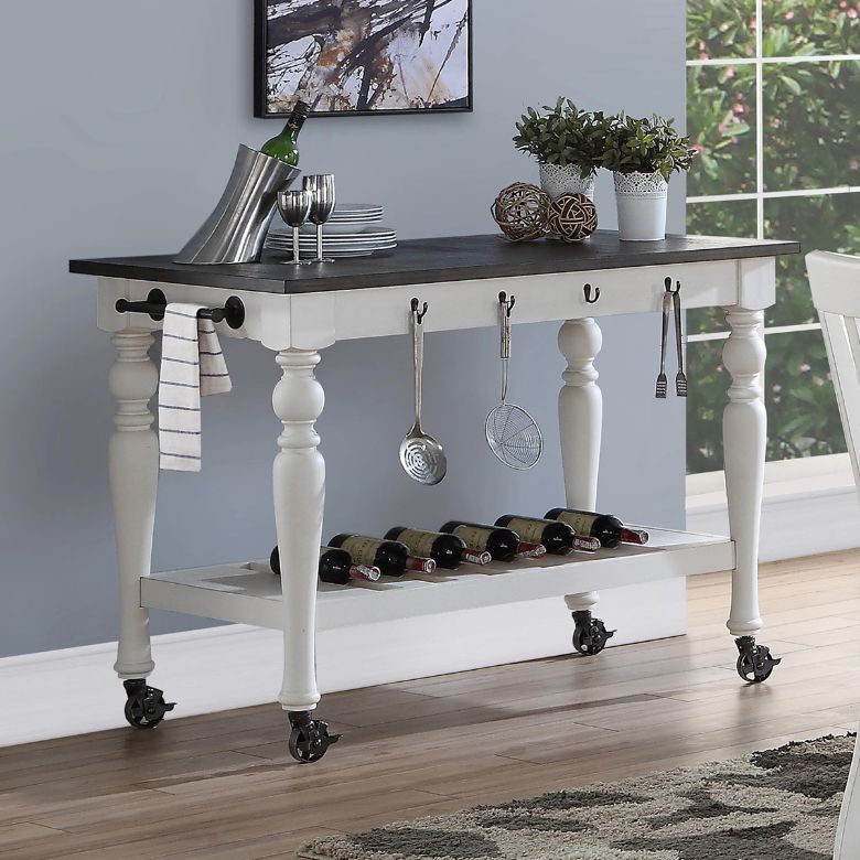 White kitchen island with dark wood top, hanging utensils, and wine storage on wheels.