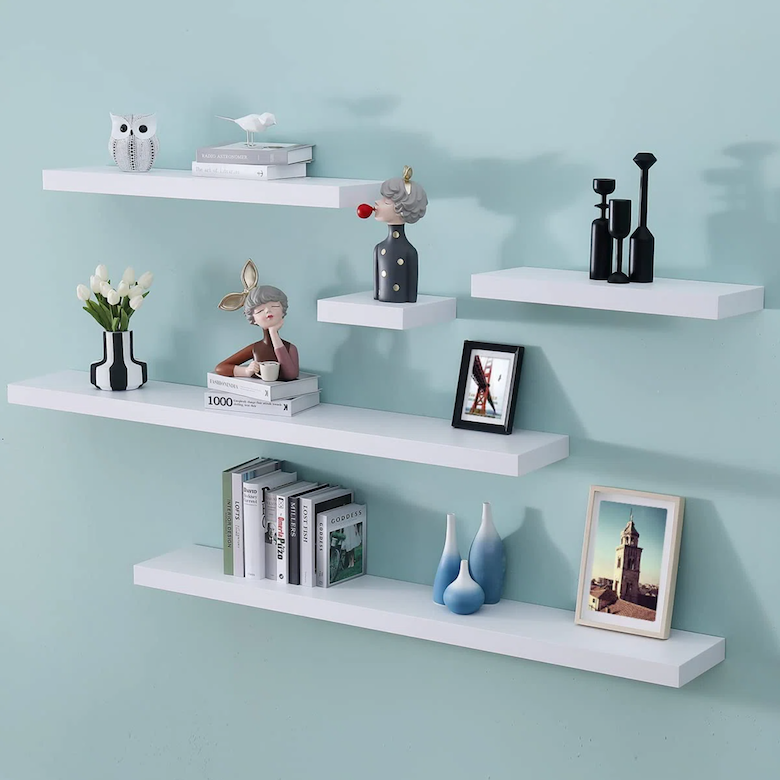 White floating wall shelves with books, vases, and decorative figurines.