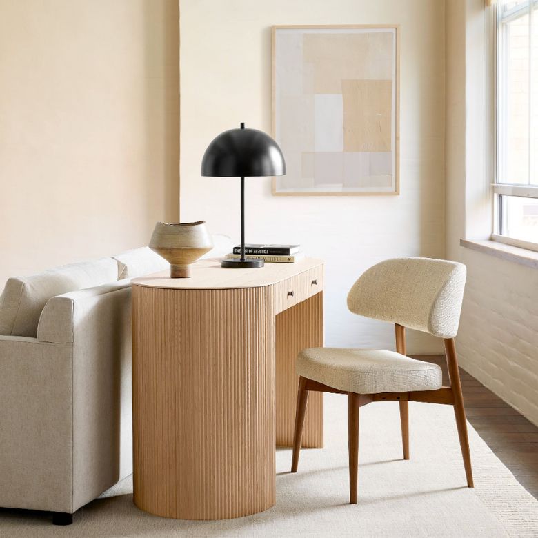 Beige living room with a curved wood console table, black dome lamp, and upholstered chair.