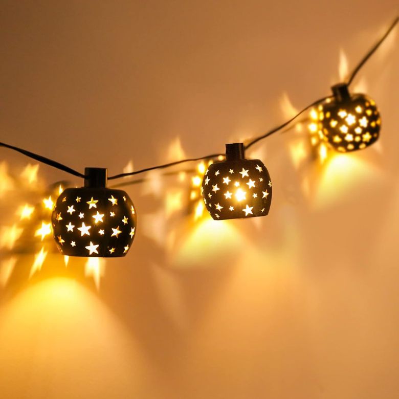 String lights with star-cut lanterns casting warm glowing patterns on the wall.