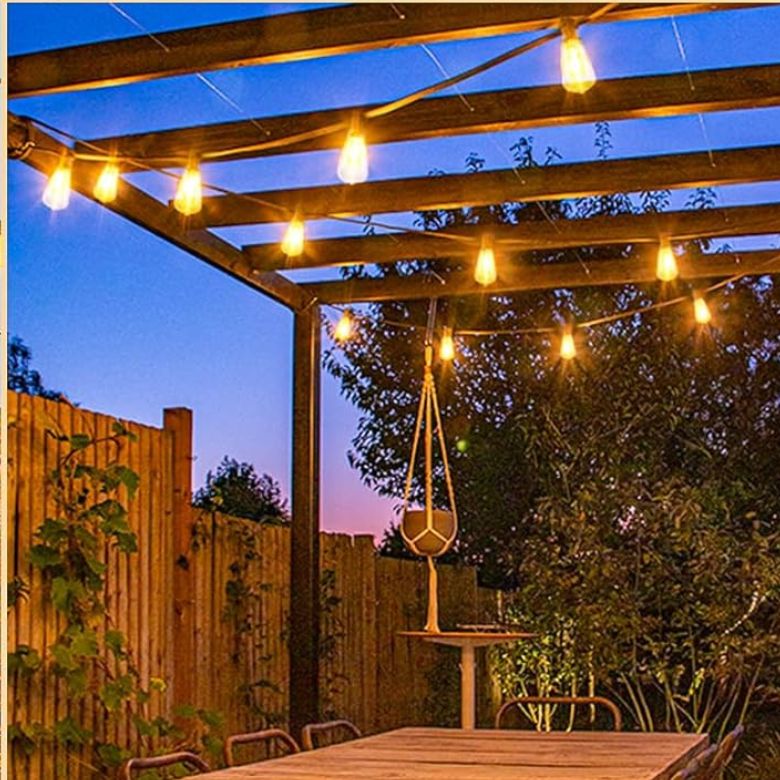 Warm string lights hanging over an outdoor patio with a pergola at dusk.