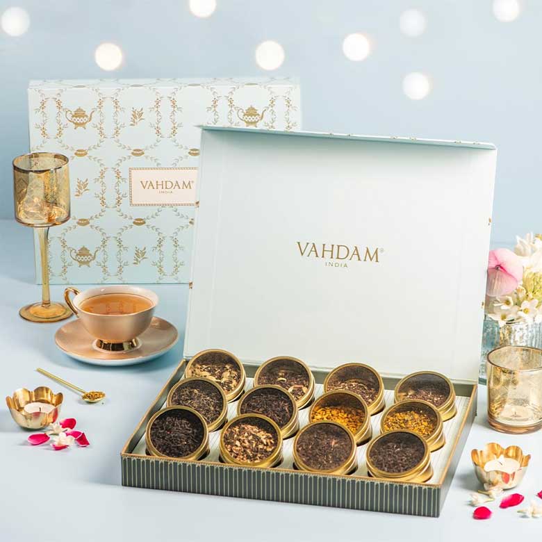 Open Vahdam tea gift box with assorted loose-leaf tea tins and decorative gold accents.