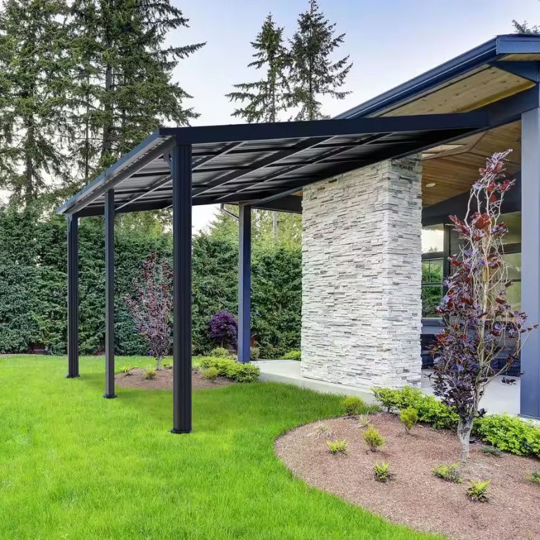 Covered outdoor patio with a black metal pergola beside a stone accent wall and landscaped garden.