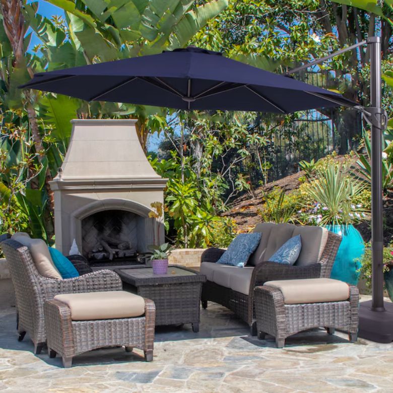 Outdoor patio with wicker seating, a fireplace, and a large umbrella.