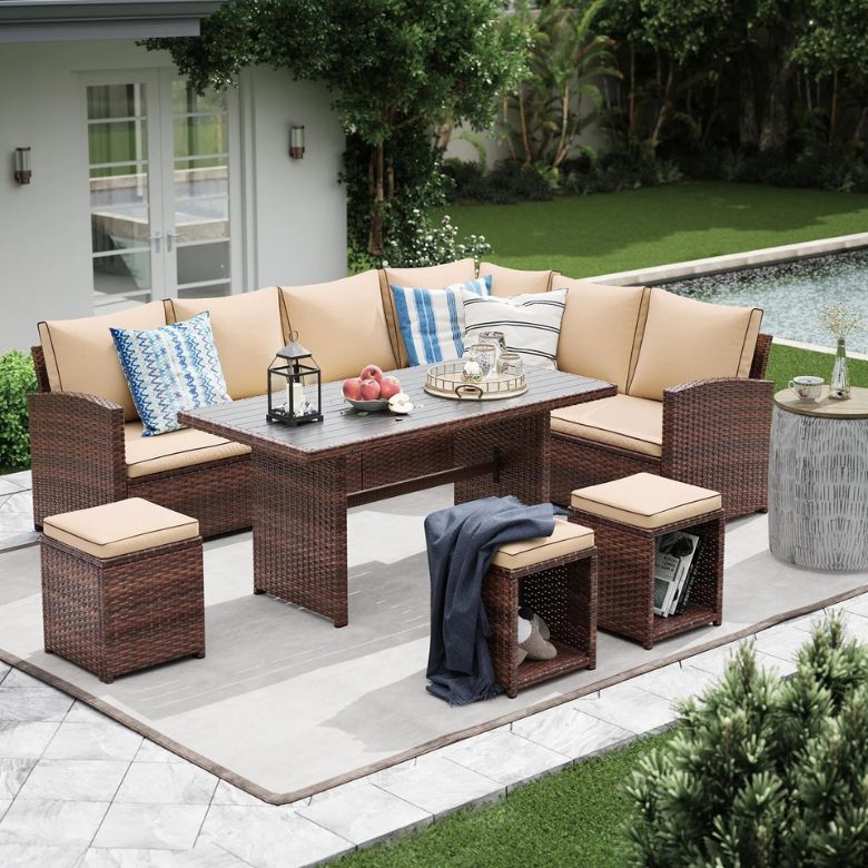 Outdoor wicker sectional dining set with cushioned seating, stools, and a rectangular table beside a pool.