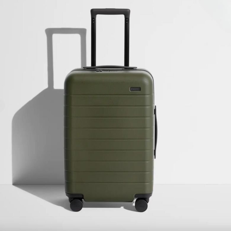 Olive green hard-shell suitcase with four spinner wheels and a telescoping handle.
