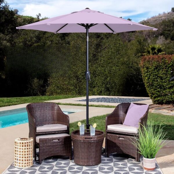 Poolside patio setup with two wicker chairs, a matching table, and a lavender umbrella on a patterned outdoor rug.