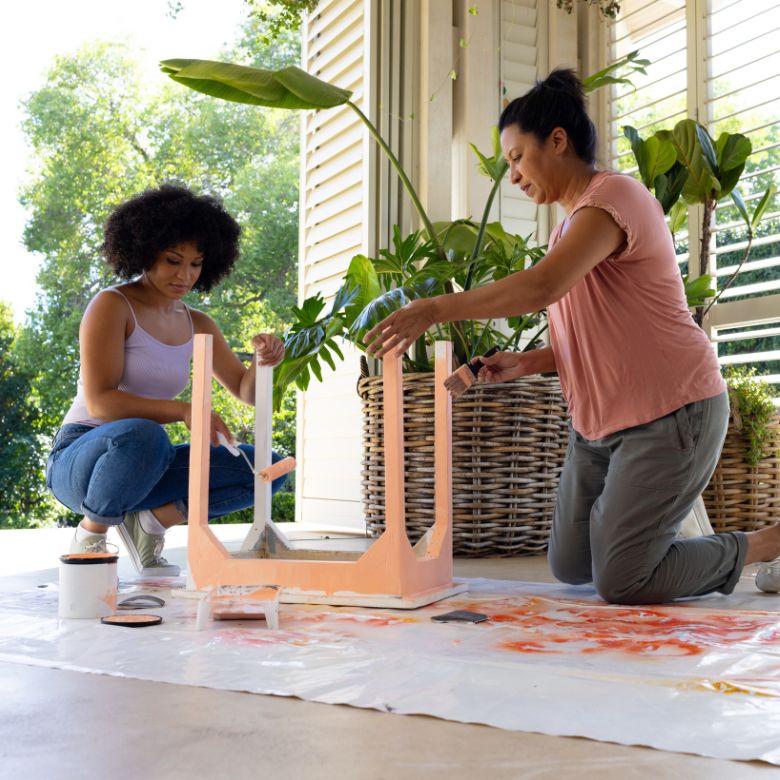 two women painting a side table