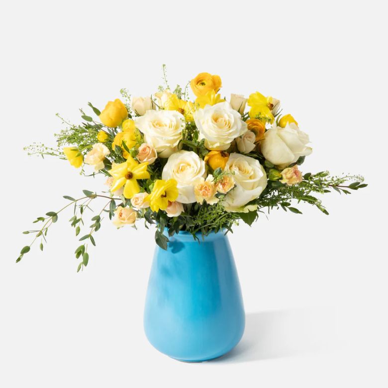 Yellow Roses, Ranunculus and Mini Carnations flower arrangement in a blue ceramic vase