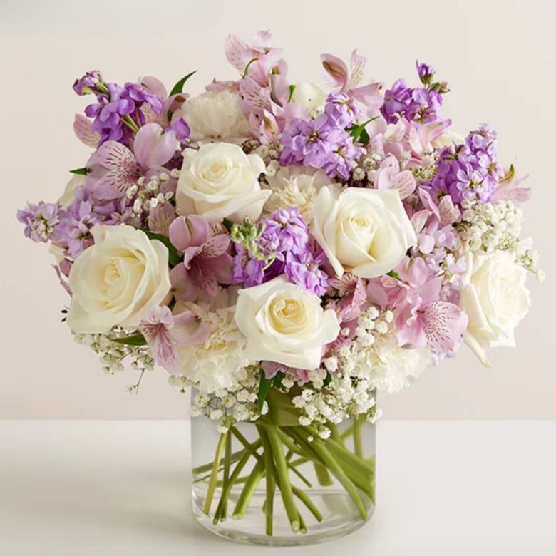 bouquet of white roses and carnations; lavender Peruvian lilies and stock; accented with baby’s breath and assorted greenery