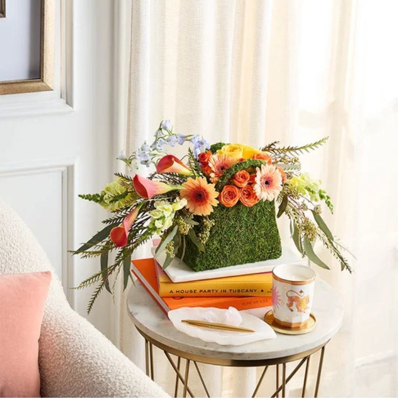 flower arrangement of orange mini calla lilies and spray roses; yellow roses and snapdragons; peach mini Gerbera daisies; light blue delphiniums; grevillea; and seeded eucalyptus